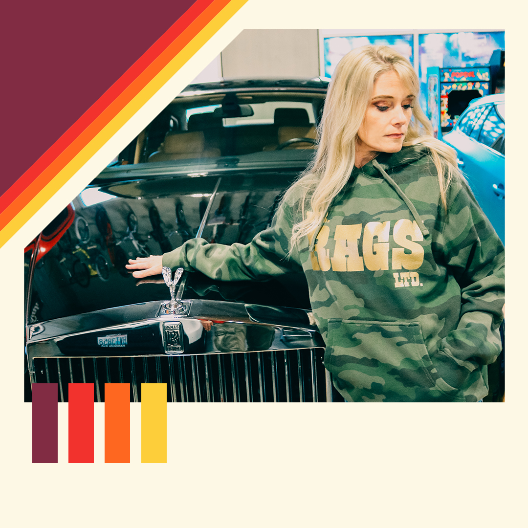 Model wearing a camouflage Mr. Rags hoodie beside a classic car